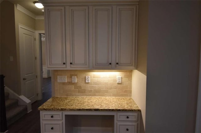 kitchen with light stone counters, built in desk, and backsplash