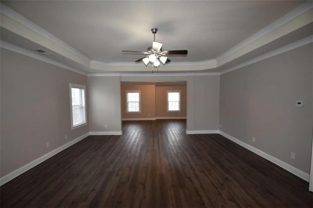 spare room featuring dark hardwood / wood-style flooring, a tray ceiling, ceiling fan, and ornamental molding