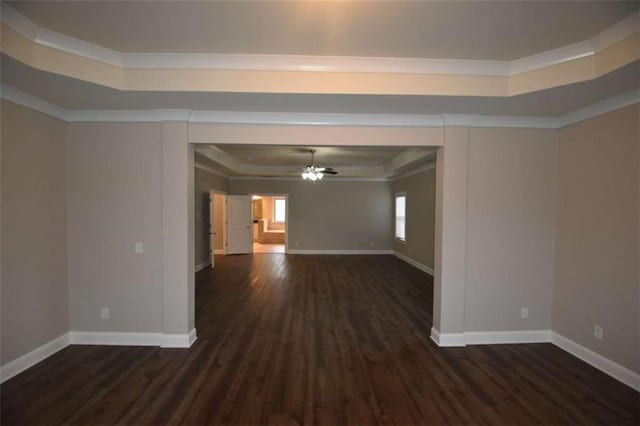 empty room featuring a raised ceiling, ceiling fan, crown molding, and dark hardwood / wood-style floors