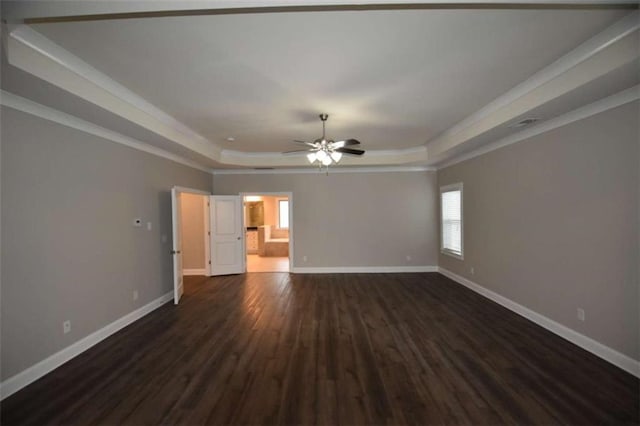 empty room featuring dark hardwood / wood-style flooring, a tray ceiling, and ceiling fan