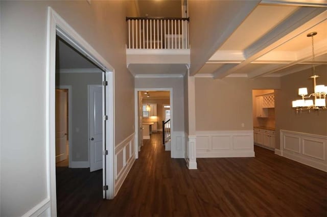 corridor with coffered ceiling, dark wood-type flooring, crown molding, beam ceiling, and a notable chandelier