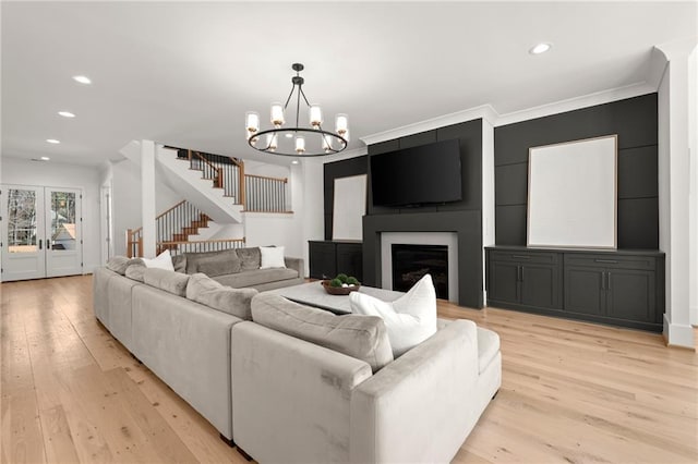 living room featuring stairway, light wood-style flooring, a fireplace, and ornamental molding