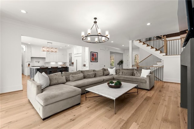 living room with light wood finished floors, recessed lighting, stairs, crown molding, and a notable chandelier