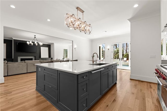 kitchen featuring double oven range, light wood-type flooring, light countertops, ornamental molding, and a sink