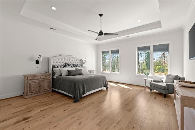 bedroom with a raised ceiling, crown molding, visible vents, and light wood-type flooring