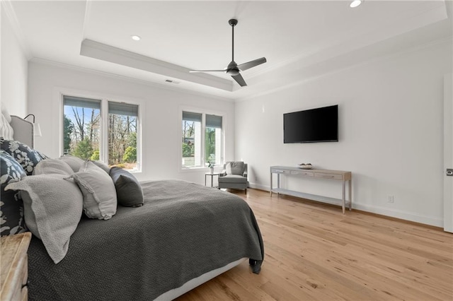 bedroom with baseboards, a raised ceiling, light wood-style floors, and ornamental molding