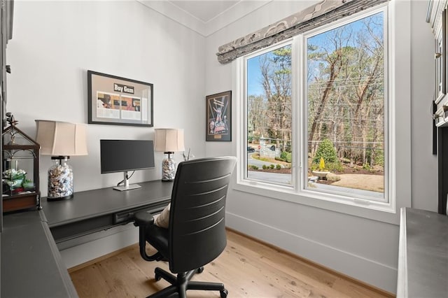 office space with light wood-style flooring, crown molding, and baseboards