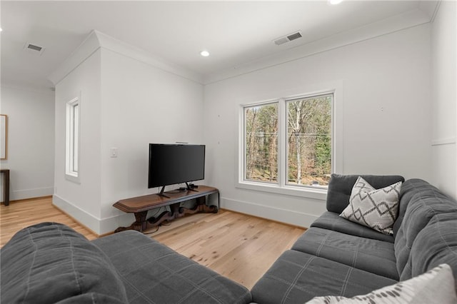 living area featuring visible vents, wood finished floors, baseboards, and ornamental molding