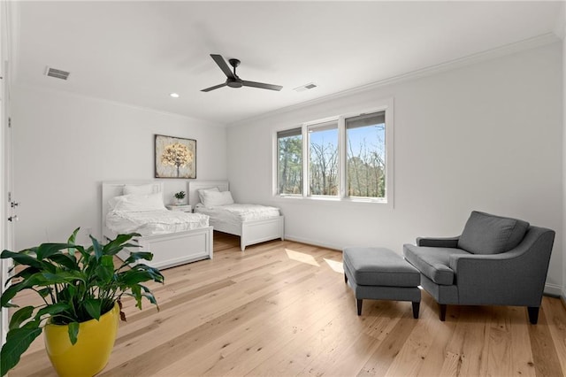 living area featuring visible vents, ceiling fan, light wood-style floors, and ornamental molding