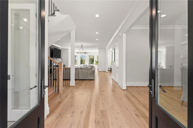 foyer featuring stairway, recessed lighting, ornamental molding, a notable chandelier, and light wood-type flooring