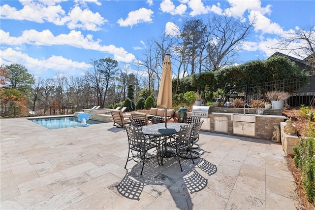 view of patio / terrace with a fenced in pool, fence, exterior kitchen, area for grilling, and a sink