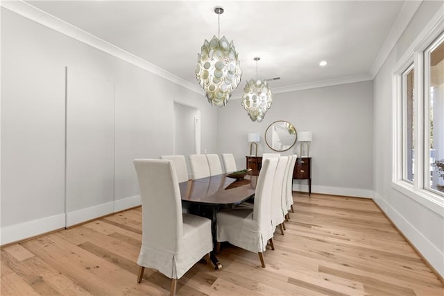 dining room featuring crown molding, light wood-style floors, and an inviting chandelier