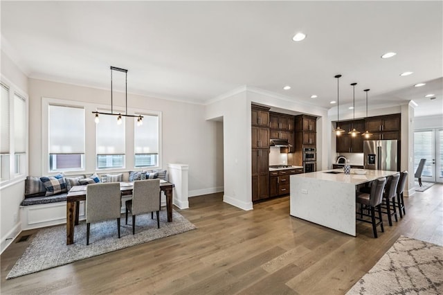 2059 Wheaton Way, Atlanta, GA 30328 - kitchen with stainless steel appliances, dark brown cabinets, baseboards, light wood finished floors, and under cabinet range hood