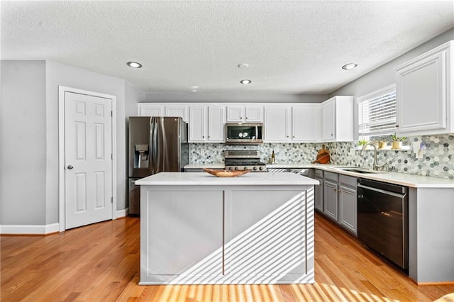 kitchen featuring a sink, light wood-style floors, appliances with stainless steel finishes, and light countertops