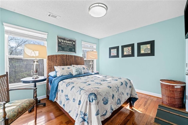 bedroom with visible vents, multiple windows, and hardwood / wood-style flooring