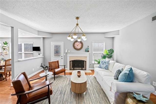 living area with a textured ceiling, wood finished floors, baseboards, and a premium fireplace