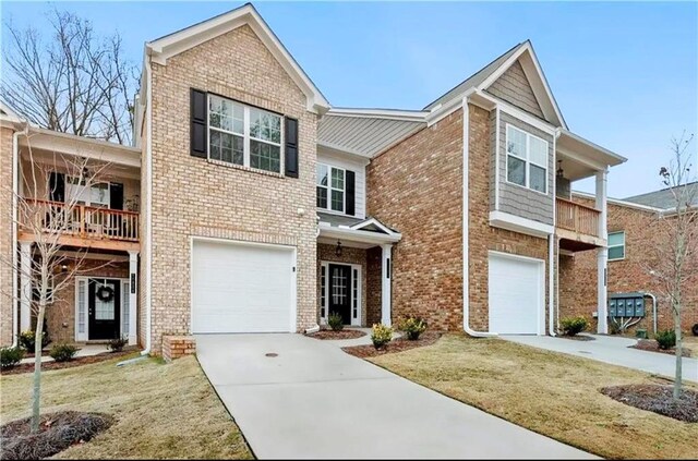 view of property featuring a garage, a balcony, and a front yard