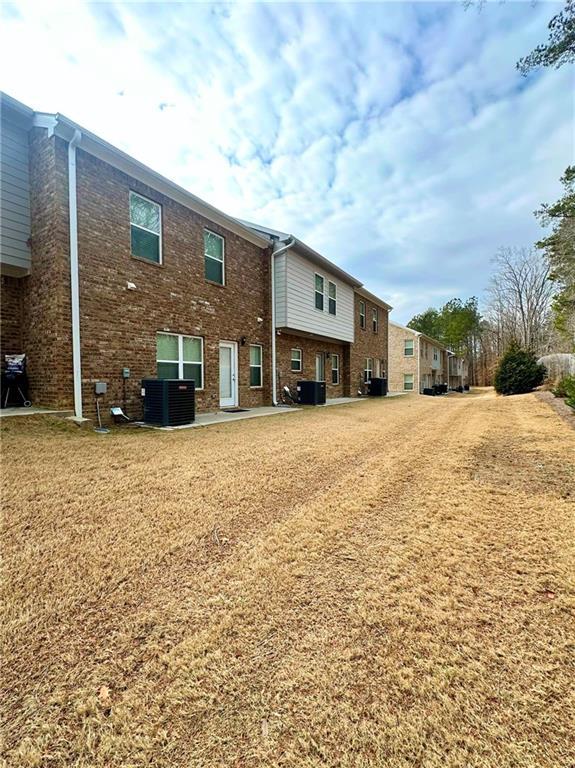 back of property featuring central air condition unit and brick siding