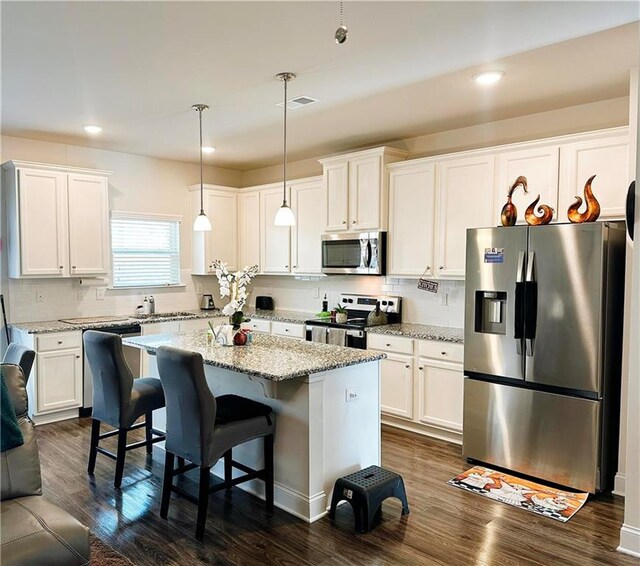 kitchen with white cabinetry, stainless steel appliances, and hanging light fixtures