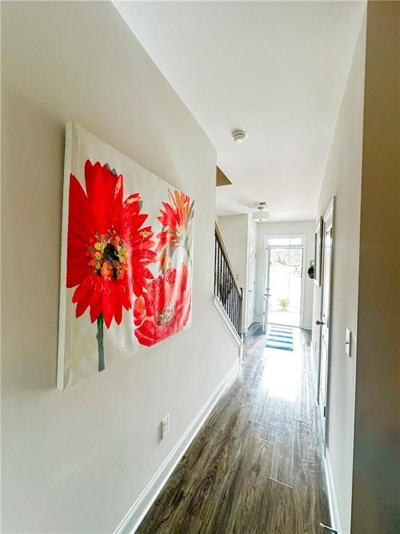 hallway with baseboards, wood finished floors, and stairs