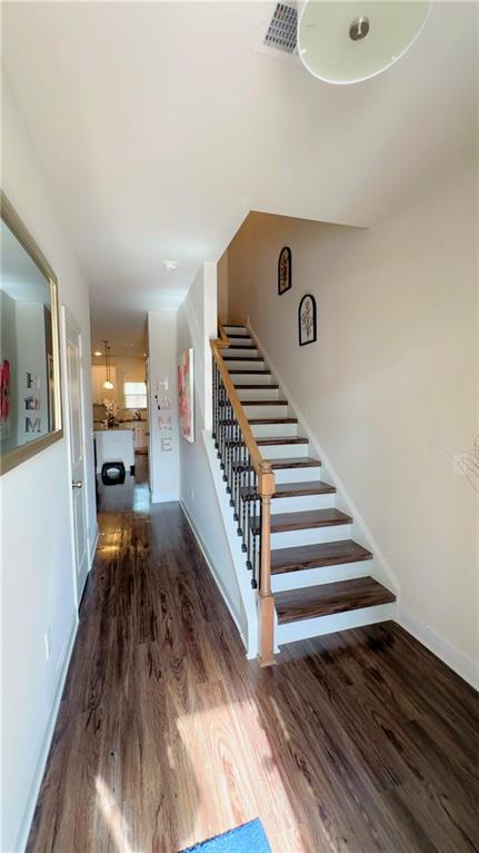 staircase featuring visible vents, baseboards, and wood finished floors