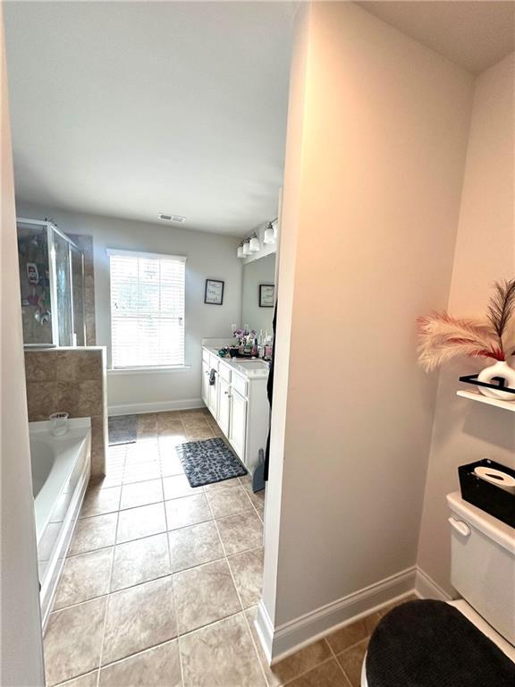 full bathroom featuring tile patterned flooring, a shower stall, baseboards, toilet, and vanity