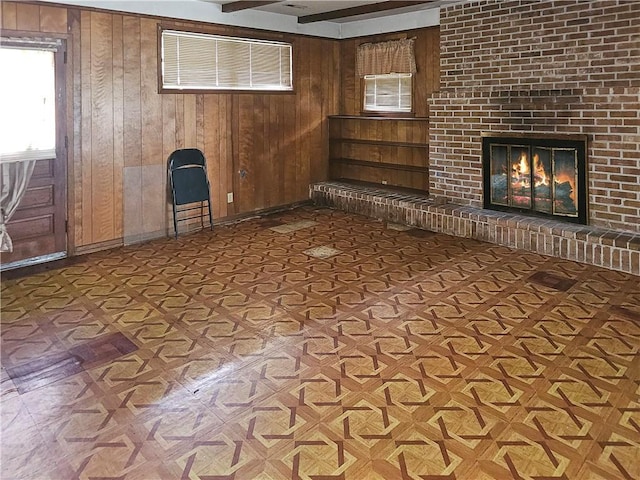 interior space featuring beamed ceiling, parquet floors, a brick fireplace, and wood walls