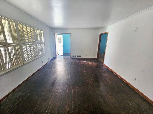 empty room featuring dark wood-type flooring and crown molding