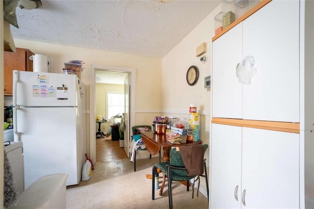 kitchen featuring freestanding refrigerator and a textured ceiling