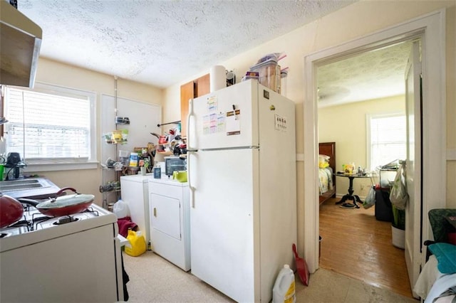 kitchen featuring freestanding refrigerator, a healthy amount of sunlight, independent washer and dryer, and a textured ceiling