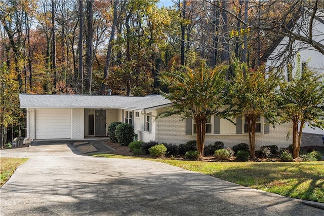 view of front facade with brick siding, an attached garage, concrete driveway, and a front lawn