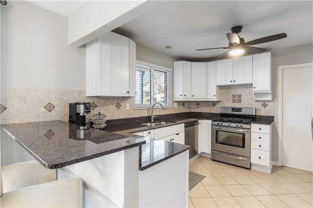 kitchen with a sink, appliances with stainless steel finishes, a peninsula, and white cabinetry