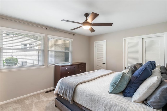 bedroom with visible vents, two closets, baseboards, light colored carpet, and a ceiling fan