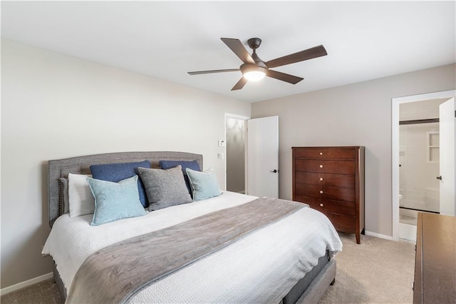 bedroom with a ceiling fan, light colored carpet, baseboards, and ensuite bathroom