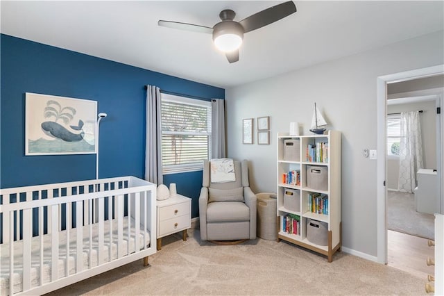 bedroom featuring multiple windows, a ceiling fan, a nursery area, and carpet floors