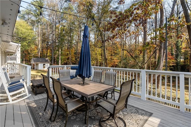 wooden terrace with outdoor dining area, a storage shed, and an outdoor structure