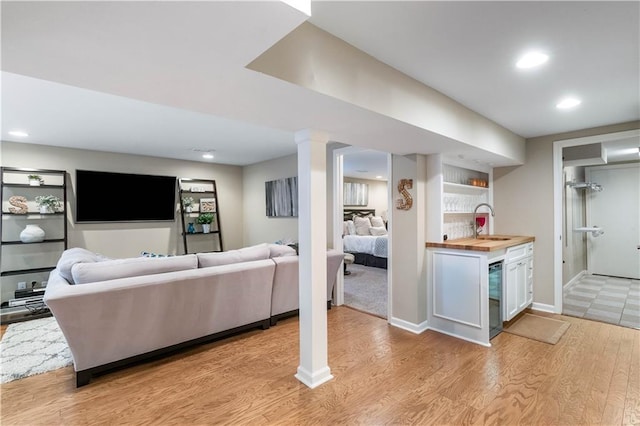 living area with recessed lighting, baseboards, wet bar, and light wood-style floors