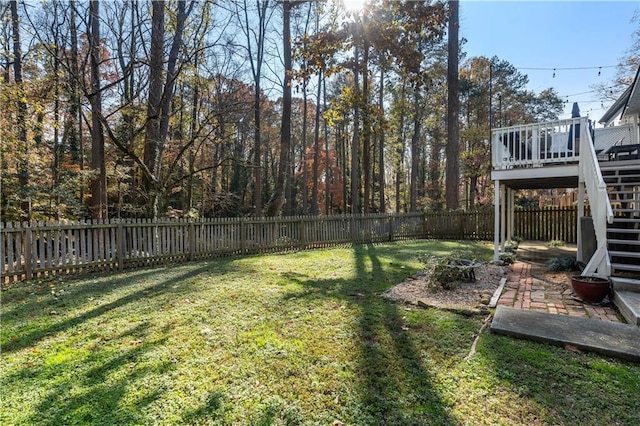 view of yard featuring stairway, a deck, a fenced backyard, and an outdoor fire pit