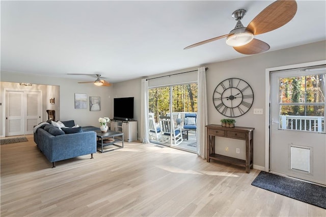 living area featuring baseboards, light wood-type flooring, and ceiling fan