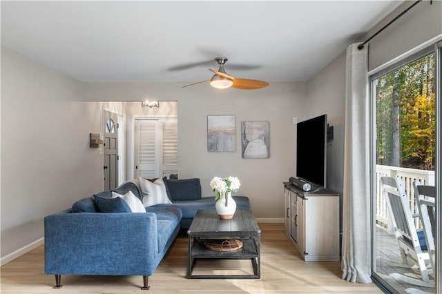 living room with a ceiling fan, baseboards, and light wood-type flooring