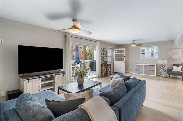 living area featuring a healthy amount of sunlight, baseboards, light wood-style flooring, and a ceiling fan