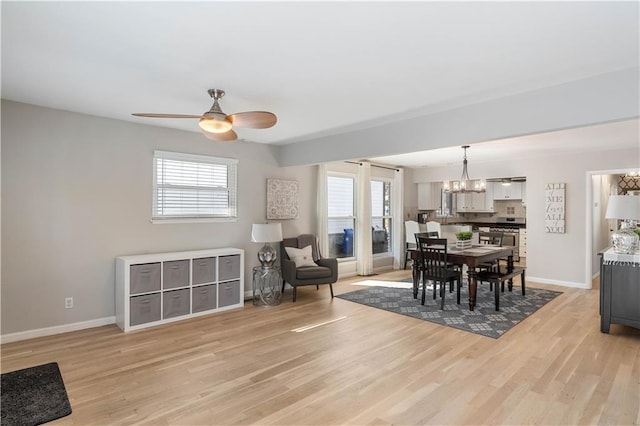 dining room featuring baseboards, ceiling fan with notable chandelier, and light wood finished floors