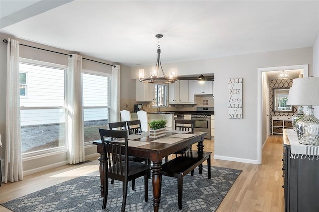 dining space with a chandelier, light wood-type flooring, and baseboards