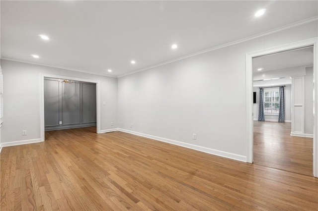 spare room featuring crown molding and light hardwood / wood-style floors