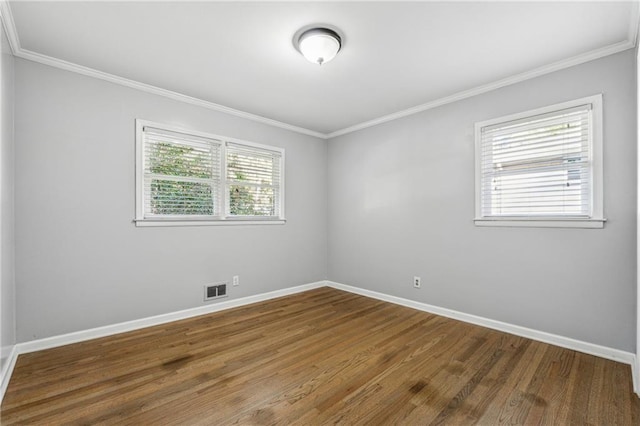 empty room with ornamental molding, a wealth of natural light, and hardwood / wood-style floors