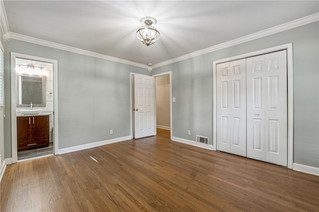 unfurnished bedroom with ornamental molding, hardwood / wood-style floors, sink, and ensuite bath