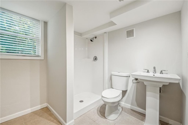 bathroom featuring tile patterned flooring, toilet, and walk in shower