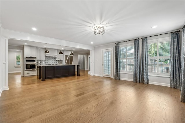 unfurnished living room featuring light hardwood / wood-style floors and crown molding