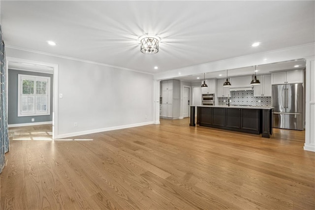 unfurnished living room with ornamental molding, light hardwood / wood-style flooring, ornate columns, and an inviting chandelier