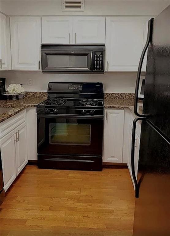 2479 Peachtree Rd Unit 503, Atlanta, GA 30305 - kitchen featuring black appliances, white cabinets, light wood finished floors, and dark stone counters